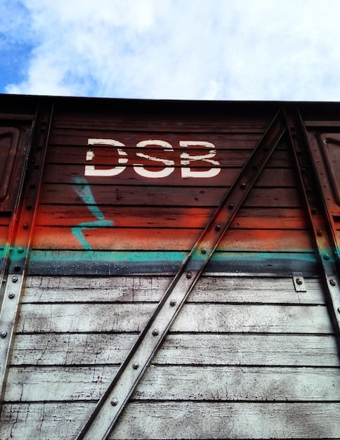 A close-up of shipping containers with various company logos at a port, with a focus on containers from different countries, illustrating the complexity of the global trade network and tariff implications.