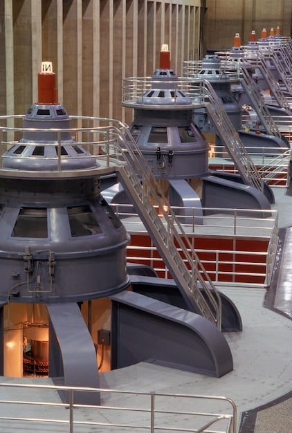 A close-up shot of the interior of a natural gas liquefaction plant, showing the complex network of pipes, valves, and machinery used in the liquefaction process. The scene is brightly lit, highlighting the industrial nature of the facility.
