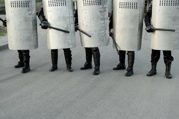 A photograph showing a group of US Border Patrol agents standing near a section of the US-Mexico border fence. The agents are equipped with patrol vehicles and other enforcement tools. The background shows the arid landscape typical of the border region.